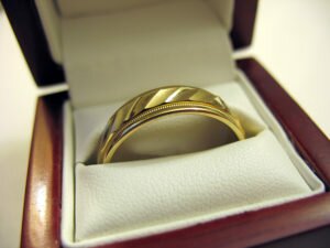 A yellow gold mens wedding band inside its box. ** Note: Shallow depth of field